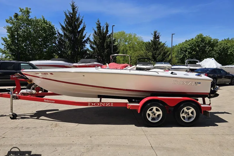 Slide: The Image of 1997 Donzi 18 Classic boat on red trailer, parked outdoors with trees in background. - 31