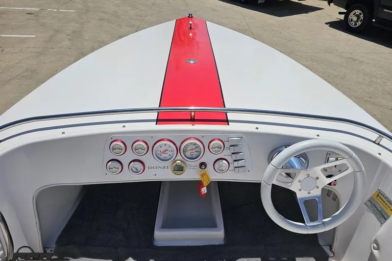 Slide: The Image of 1997 Donzi 18 Classic boat dashboard with red stripe, gauges, and white steering wheel. - 59