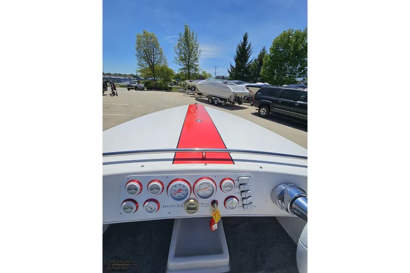 Slide: The Image of 1997 Donzi 18 Classic boat dashboard with red stripe, parked outdoors under clear blue sky. - 64