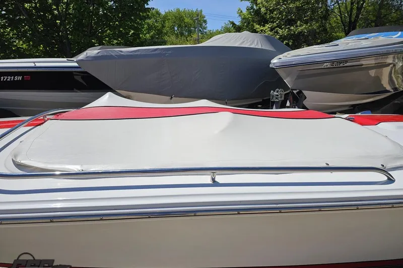Slide: The Image of 1997 Donzi 18 Classic boat with red and white cover, parked among other boats. - 82
