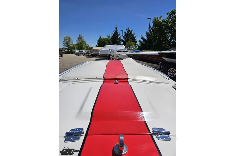 Slide: The Image of 1997 Donzi 18 Classic boat with red stripe, parked outdoors under clear blue sky. - 83