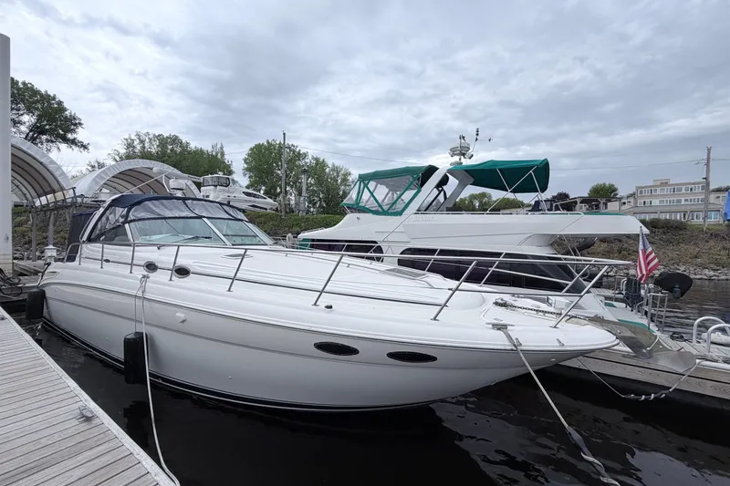 The Image of 2001 Sea Ray 380 Sundancer yacht docked at marina under cloudy sky. - 0