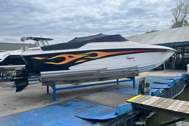 The Image of 2000 Donzi 33 ZX speedboat with flame graphics, docked at a marina under cloudy skies. - 1