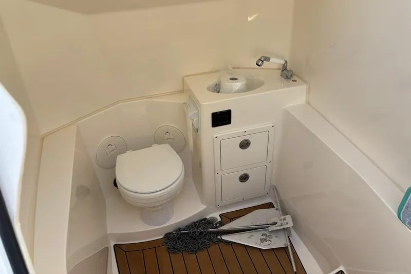 Slide: The Image of 2023 Cobia 301 Center Console boat bathroom with toilet, sink, and storage. - 13