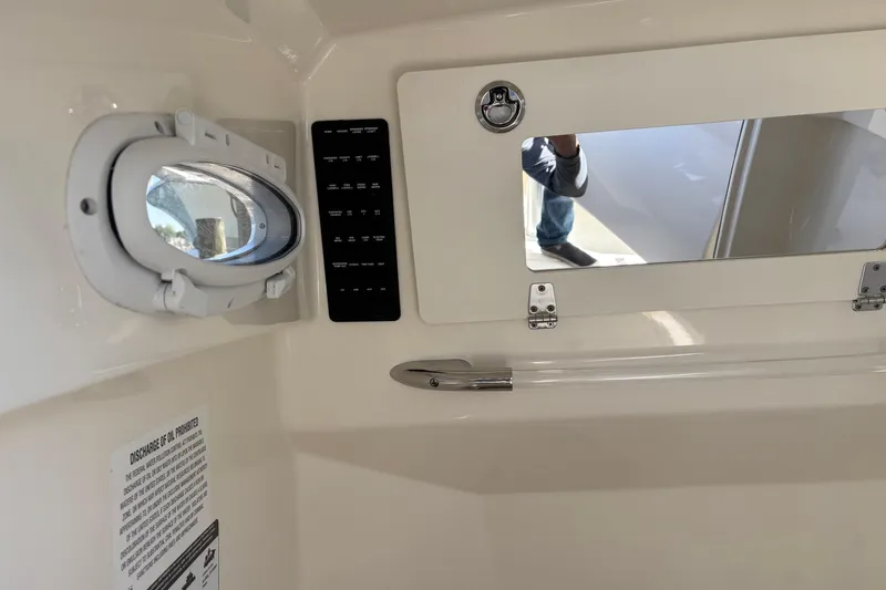 Slide: The Image of Interior view of 2023 Cobia 301 Center Console boat, featuring a porthole and control panel. - 14
