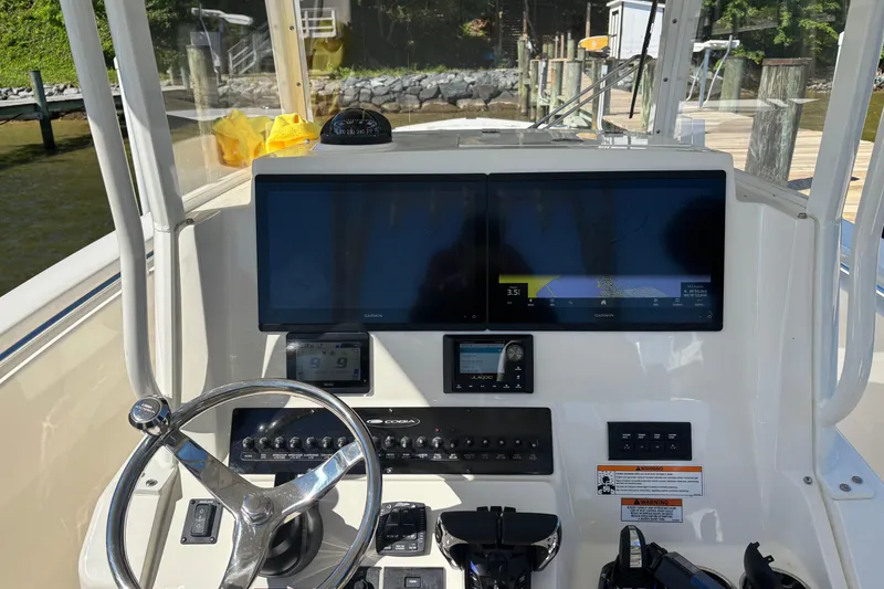 Slide: The Image of 2023 Cobia 301 Center Console helm with dual Garmin displays and steering wheel. - 2