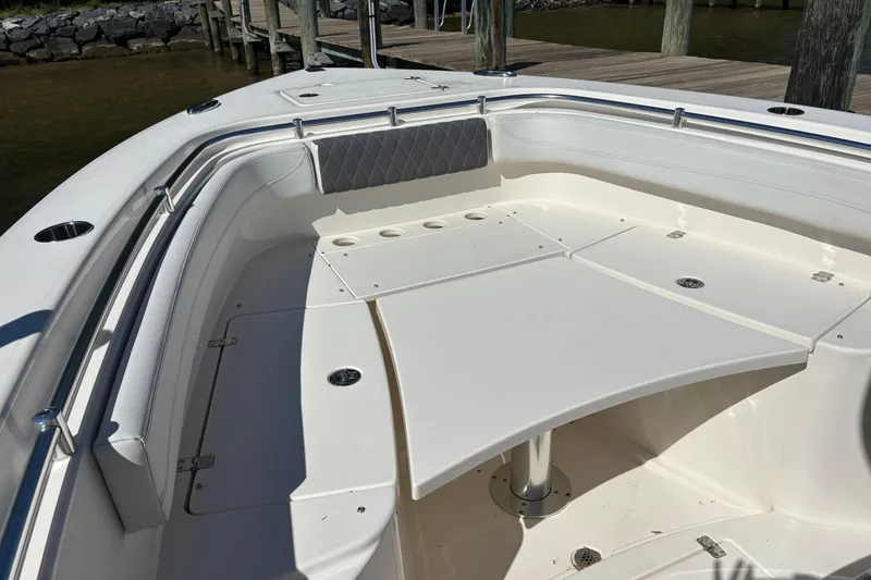 Slide: The Image of 2023 Cobia 301 Center Console boat interior with seating and table, docked by wooden pier. - 20