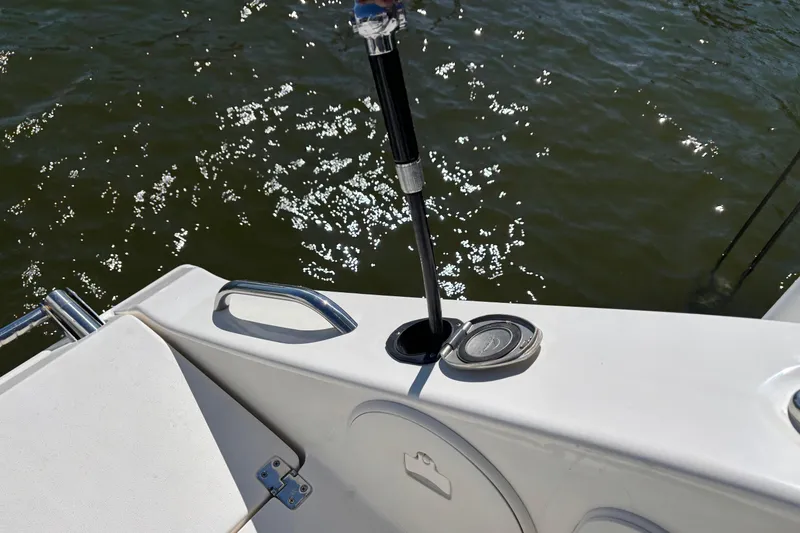 Slide: The Image of 2023 Cobia 301 Center Console boat detail with rod holder and water reflections. - 24