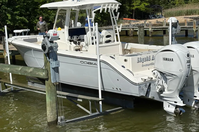 Slide: The Image of 2023 Cobia 301 Center Console boat with Yamaha engines docked by the shore. - 3