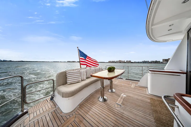 Slide: The Image of Luxurious 2011 Hunt 52 yacht deck with seating, table, and American flag on open water. - 7