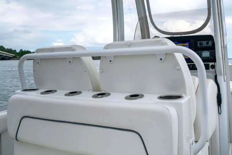 Slide: The Image of 2014 Sea Hunt Gamefish 27 boat interior with seating and control panel on a calm waterway. - 8