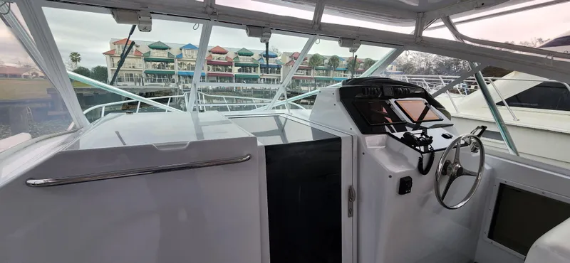 Slide: The Image of 1995 Cabo 35 Express boat interior with steering wheel and marina view. - 11