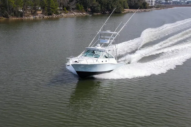 Slide: The Image of 1995 Cabo 35 Express boat cruising on a calm river, surrounded by trees. - 73