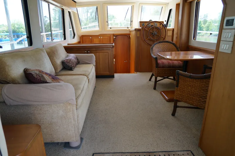 Slide: The Image of Interior of a Mainship boat featuring a cozy sofa, dining area, and helm station. - 10