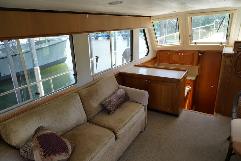 Slide: The Image of Interior of a Mainship boat featuring a cozy sofa, wooden cabinetry, and large windows. - 11