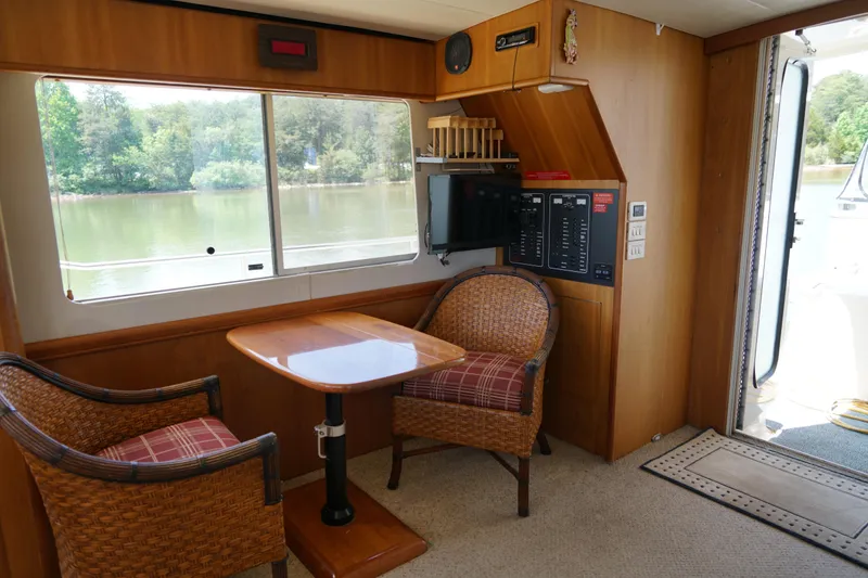 Slide: The Image of Cozy Mainship boat interior with wicker chairs, wooden table, and scenic window view. - 12