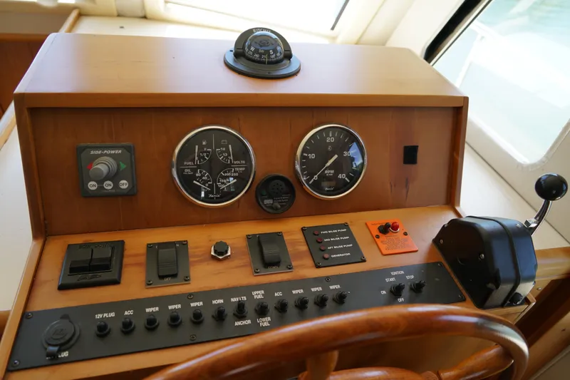 Slide: The Image of Mainship boat control panel with gauges, switches, and throttle lever in a wooden dashboard. - 16
