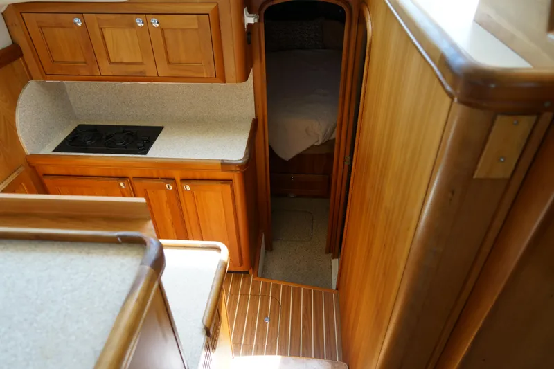 Slide: The Image of Mainship boat interior with wooden cabinetry, compact kitchen, and cozy sleeping area. - 17