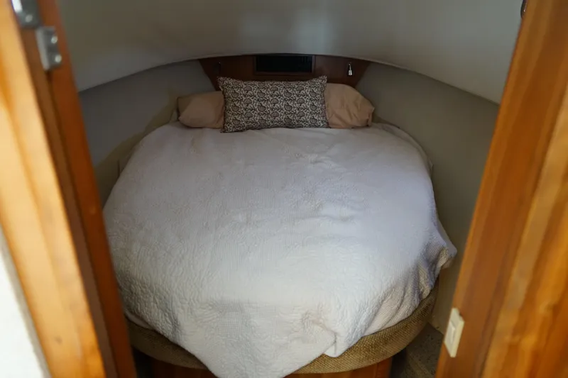 Slide: The Image of Cozy Mainship boat cabin with a neatly made bed and decorative pillows. - 20