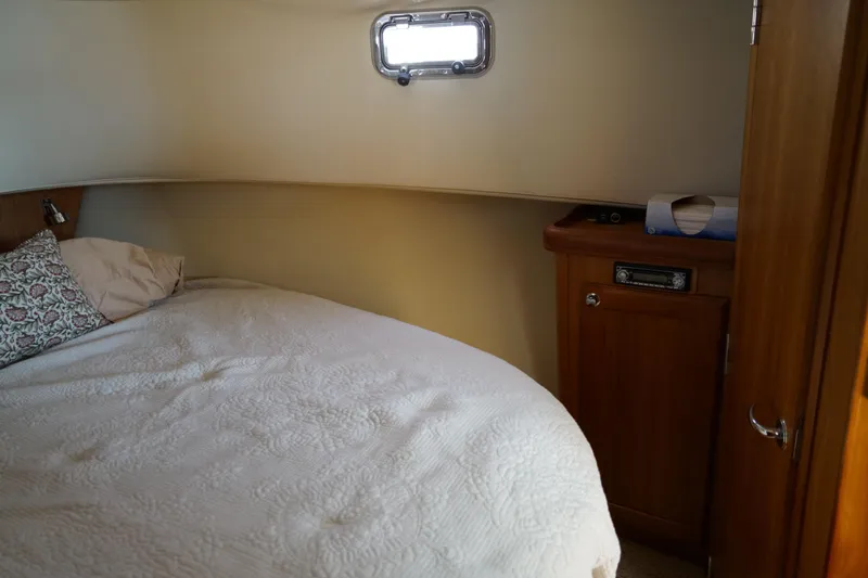 Slide: The Image of Cozy Mainship boat cabin with bed, wooden cabinet, and small window. - 21
