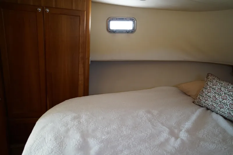Slide: The Image of Cozy Mainship boat cabin with bed, wooden wardrobe, and small window. - 22