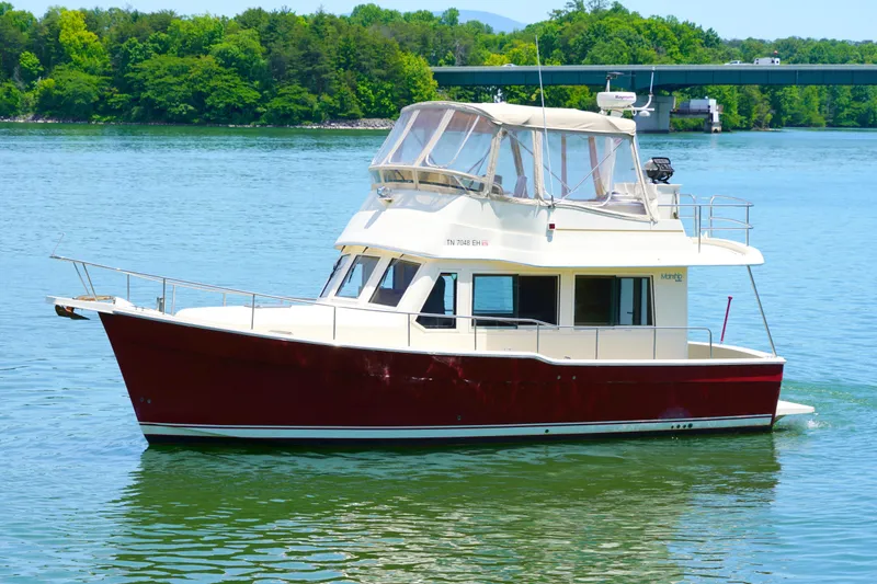 Slide: The Image of Red Mainship boat cruising on a serene lake with lush green trees in the background. - 3
