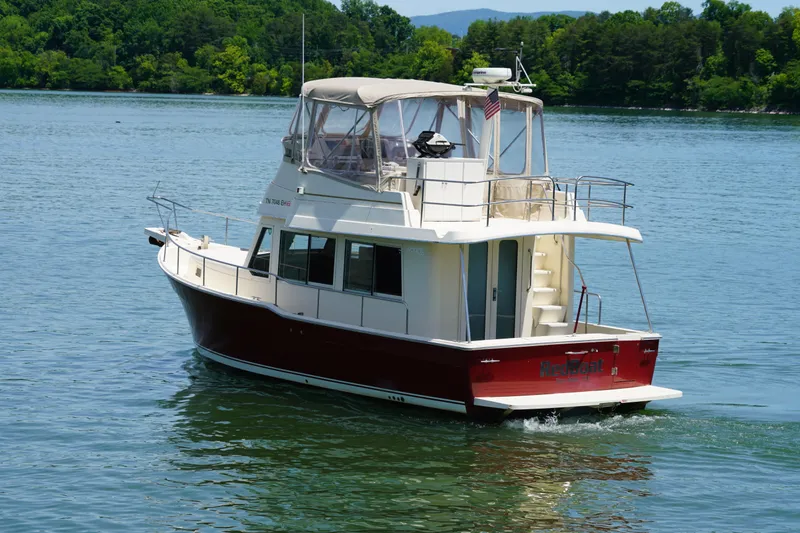 Slide: The Image of Mainship boat cruising on a serene lake with lush green trees in the background. - 4
