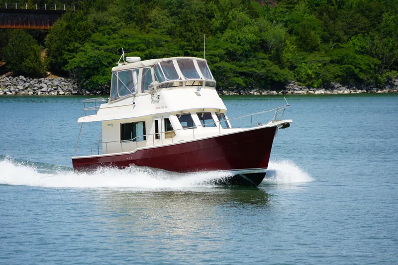 Slide: The Image of Mainship boat cruising on a serene lake with lush green shoreline. - 5