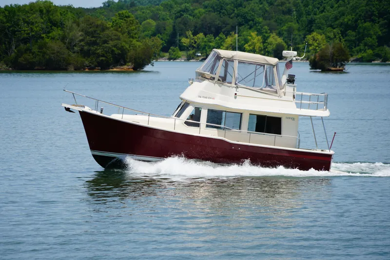 Slide: The Image of Mainship boat cruising on a serene lake with lush green forest background. - 7