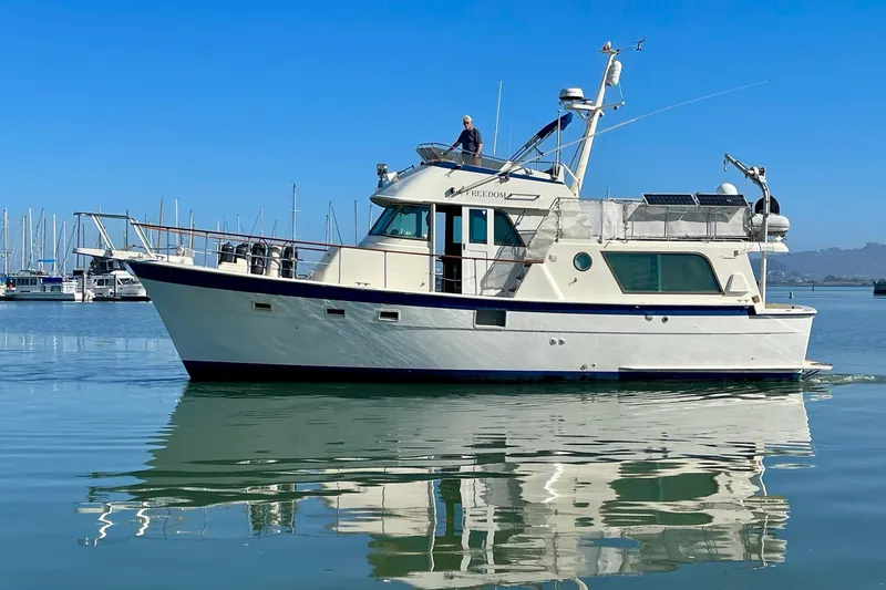 Slide: The Image of 1976 Hatteras 48 Long Range Cruiser on calm water, clear blue sky background. - 1