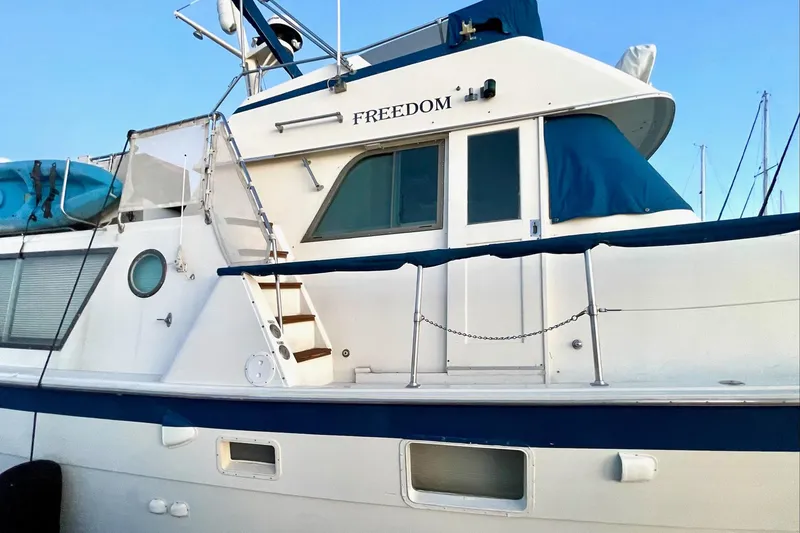 Slide: The Image of 1976 Hatteras 48 Long Range Cruiser yacht with blue accents and "Freedom" on the side. - 11
