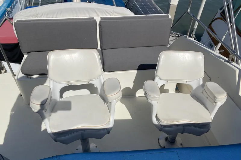 Slide: The Image of Two white captain chairs on a 1976 Hatteras 48 Long Range Cruiser deck. - 34