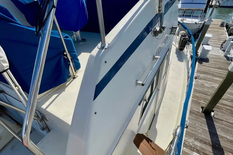 Slide: The Image of 1976 Hatteras 48 Long Range Cruiser docked, featuring blue accents and stainless steel railings. - 37