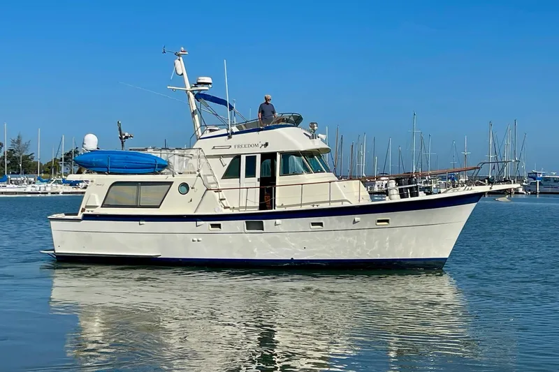 Slide: The Image of 1976 Hatteras 48 Long Range Cruiser yacht docked in a marina, clear blue sky. - 4