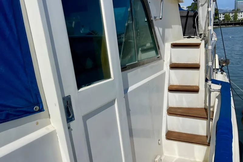 Slide: The Image of 1976 Hatteras 48 Long Range Cruiser with wooden steps and blue canvas cover. - 41