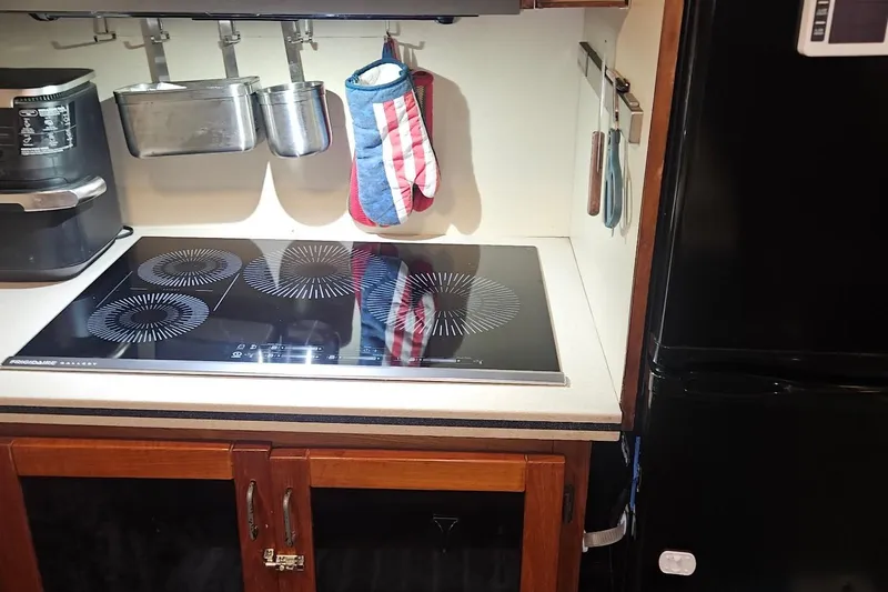 Slide: The Image of Modern kitchen in 1976 Hatteras 48 Long Range Cruiser with induction cooktop and utensils. - 45