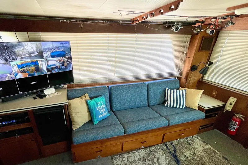 Slide: The Image of Interior of 1976 Hatteras 48 Long Range Cruiser with blue sofa, TV, and fishing rods. - 49