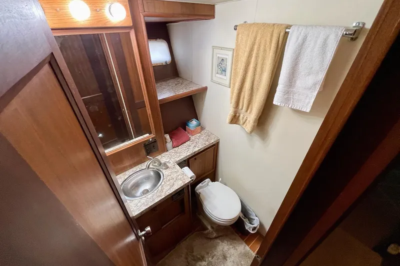 Slide: The Image of Bathroom interior of 1976 Hatteras 48 Long Range Cruiser with sink, toilet, and towels. - 56