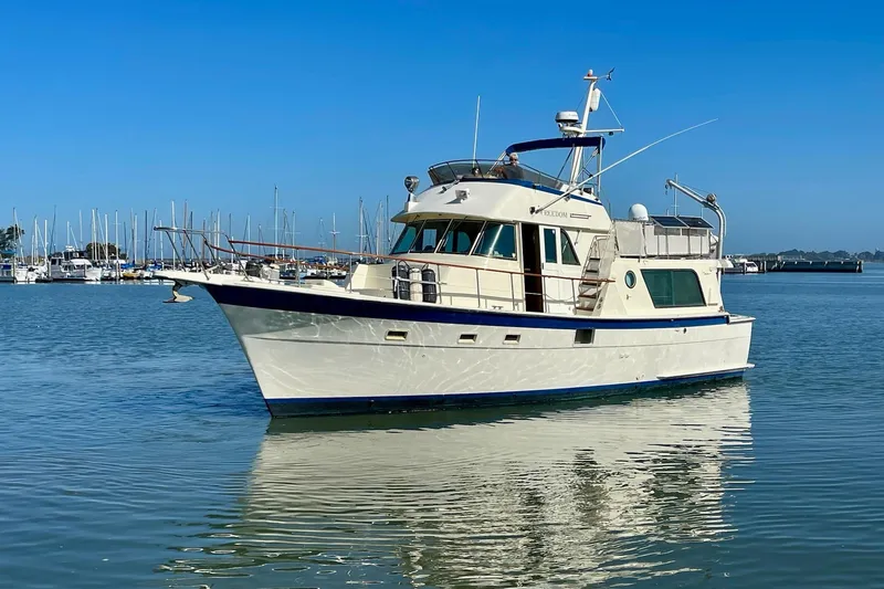 Slide: The Image of 1976 Hatteras 48 Long Range Cruiser on calm water, marina in background. - 81