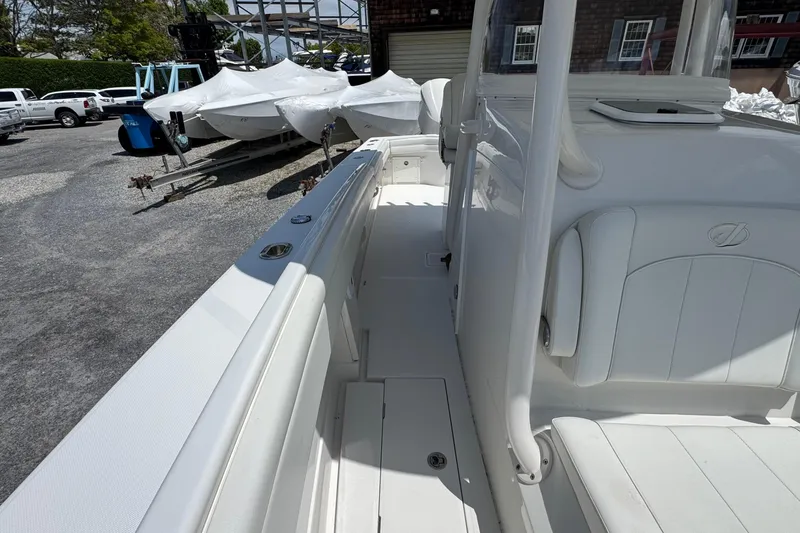 Slide: The Image of 2013 Jupiter 32 Cuddy boat interior with white seating and deck, parked outdoors. - 26