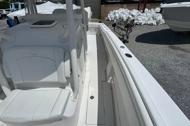 Slide: The Image of 2013 Jupiter 32 Cuddy boat interior with white seating and deck, parked on gravel. - 29