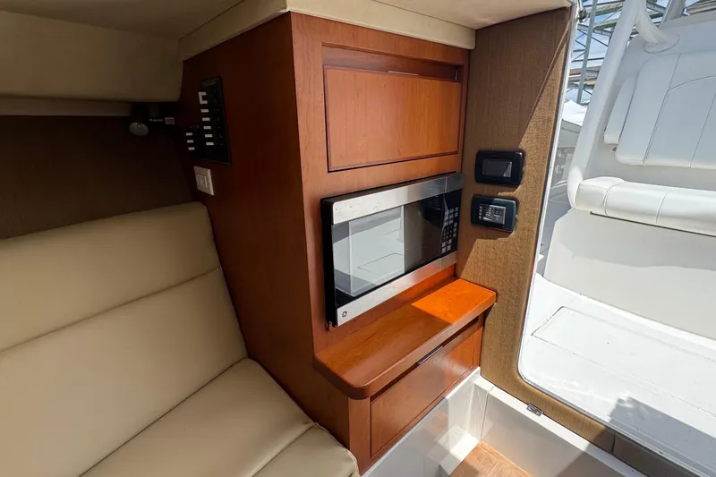 Slide: The Image of Interior of 2013 Jupiter 32 Cuddy boat featuring a microwave and seating area. - 39