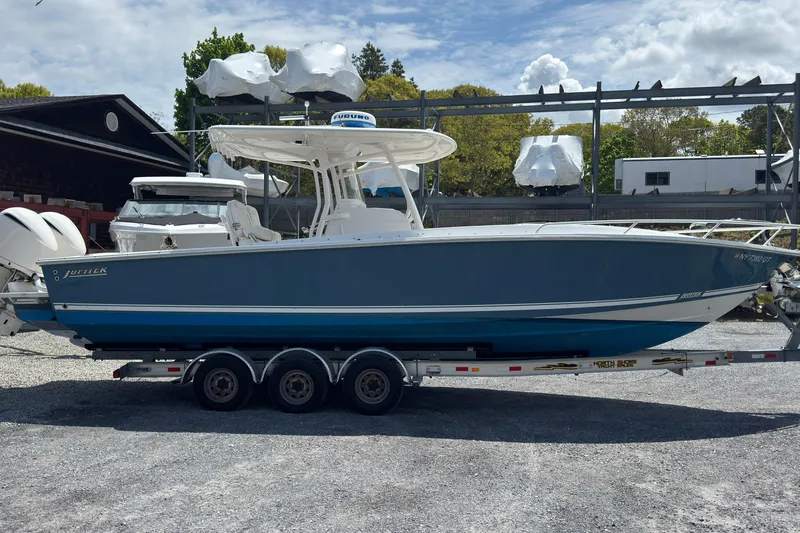 Slide: The Image of 2013 Jupiter 32 Cuddy boat on trailer, parked outdoors under a partly cloudy sky. - 4