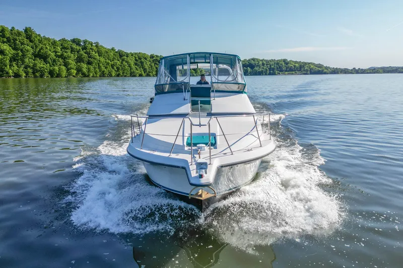 Slide: The Image of 1994 Carver 380 Santego cruising on a serene lake with lush green shoreline. - 7