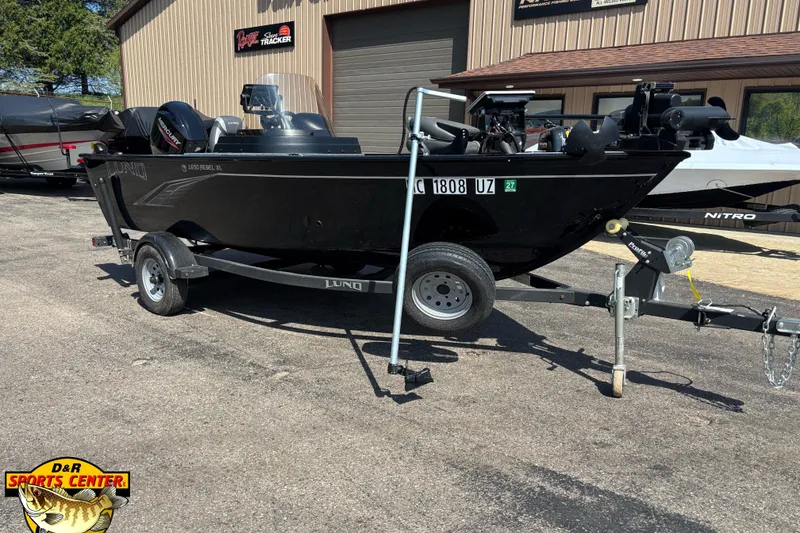The Image of 2023 Lund 1650 Rebel XL SS boat on trailer at dealership, sunny day. - 0