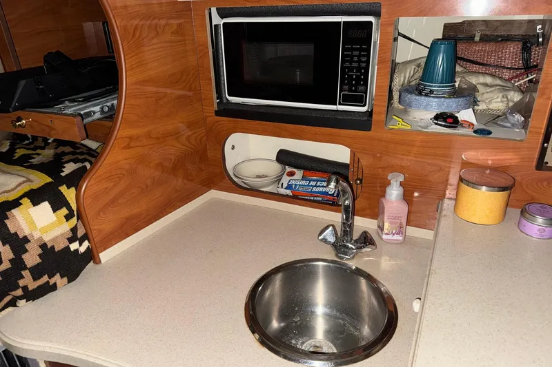 Slide: The Image of 2002 Rinker Fiesta Vee 310 boat interior with sink, microwave, and wooden cabinetry. - 15