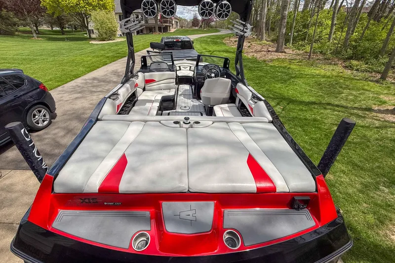 Slide: The Image of 2016 Axis A22 boat with red and gray interior, parked on a driveway. - 11
