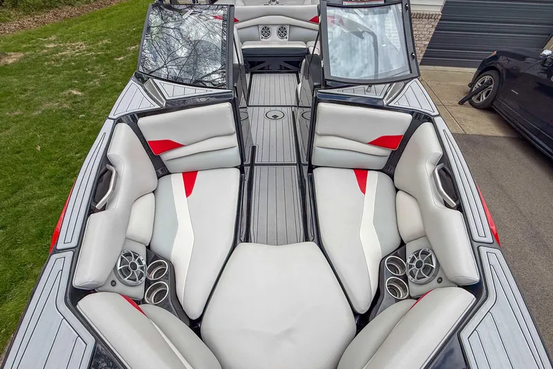 Slide: The Image of 2016 Axis A22 boat interior with gray and red seating, cup holders, and open windshield. - 15