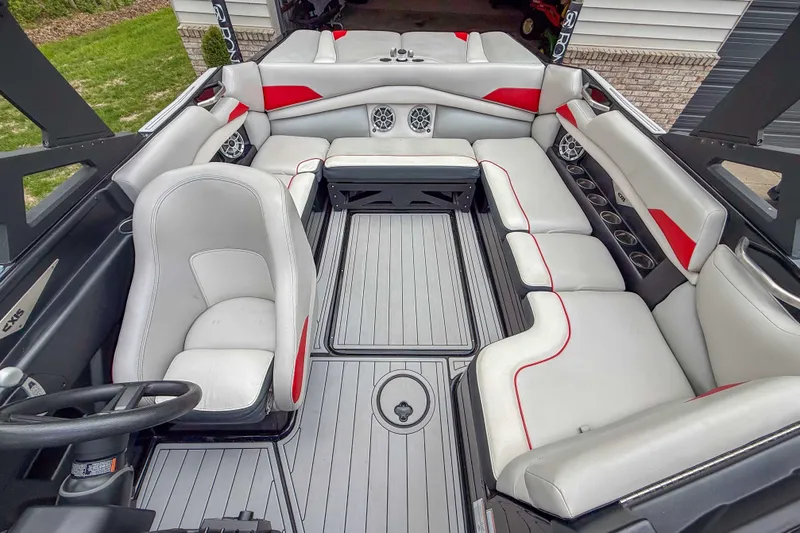 Slide: The Image of 2016 Axis A22 boat interior with gray and red seating, cup holders, and steering wheel. - 16