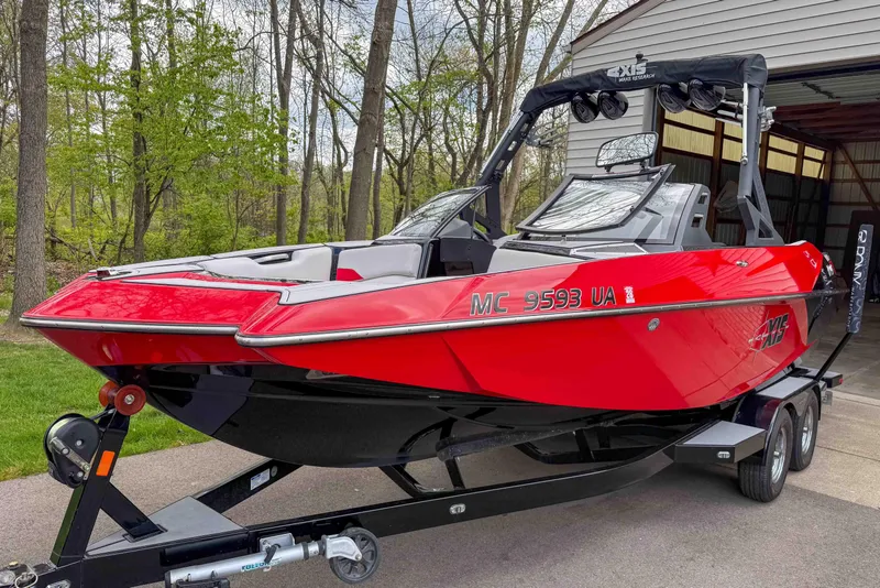 Slide: The Image of Red 2016 Axis A22 boat on trailer, parked near a wooded area. - 3